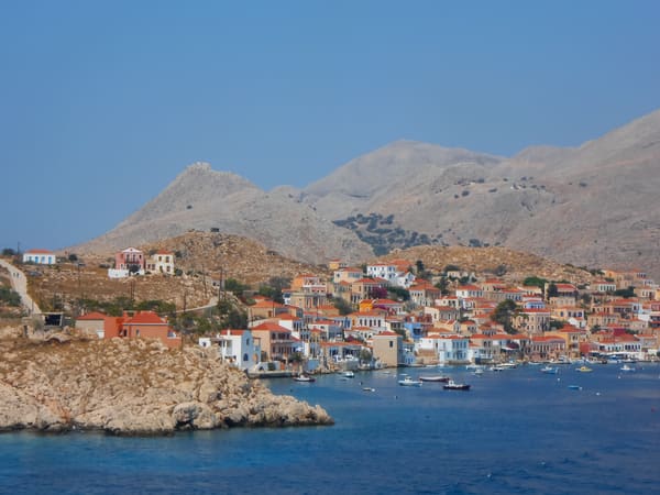 Colourful houses of Emborio harbour on Chalki below bare mountains
