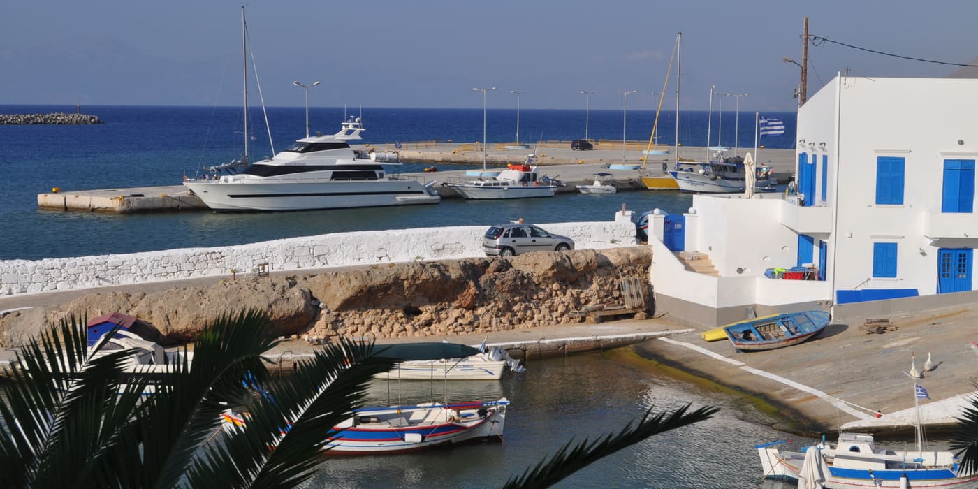 Fishing boats and a white house with blue shutters in a harbour on Kasos