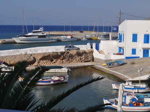 Fishing boats and a white house with blue shutters in a harbour on Kasos
